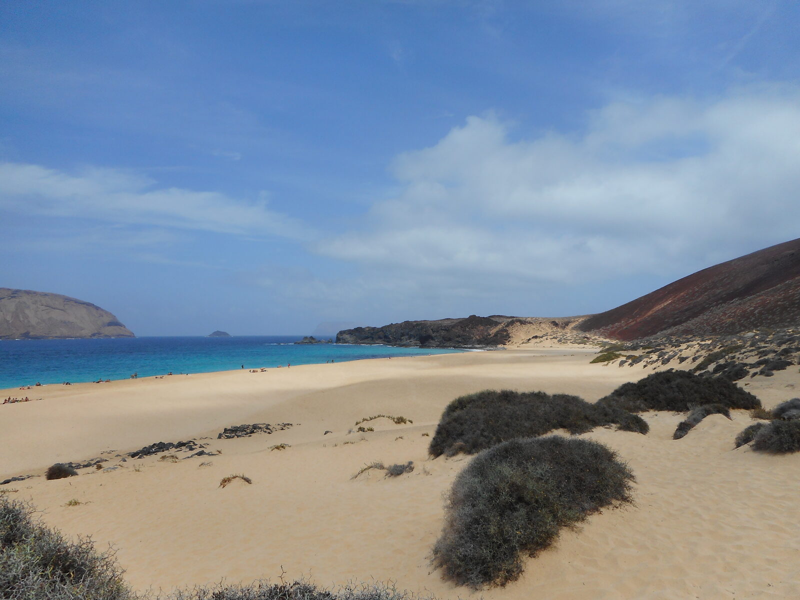 Playa de las Conchas on the north coast of La Graciosa, pale sand framed by red volcanic cone Montaña Bermeja