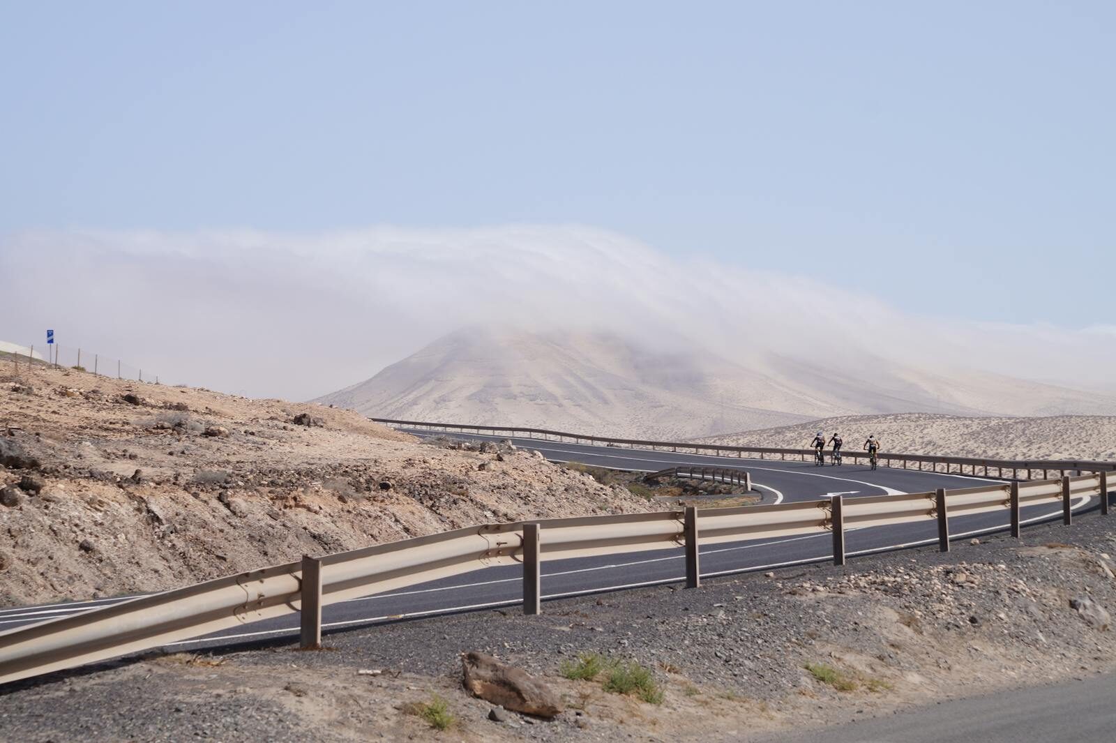 Road cyclists on a curving Canary Islands road through arid mountainous terrain